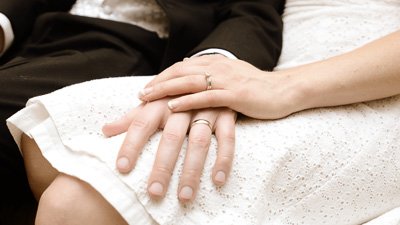 Hochzeitspaar hält Händchen mit Trauring am Finger